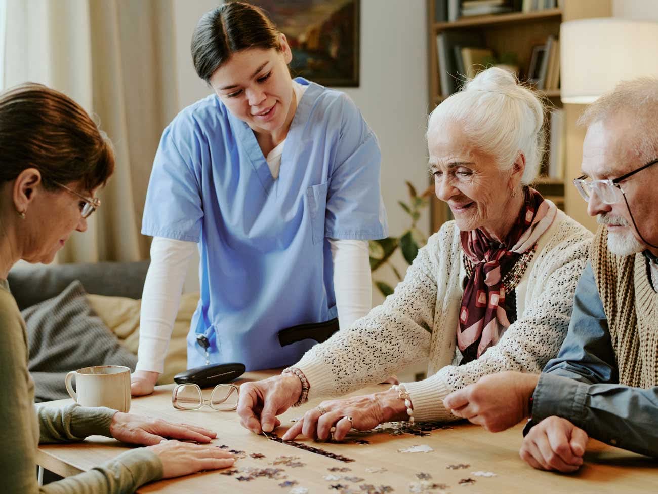 Caregiver assists seniors assembling a jigsaw puzzle at home