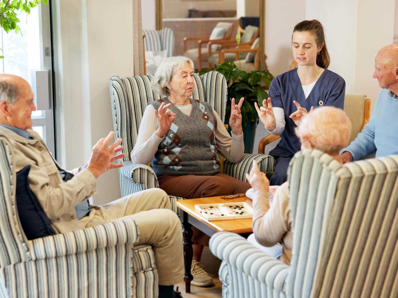 Caregiver leads seated seniors in group hand exercise