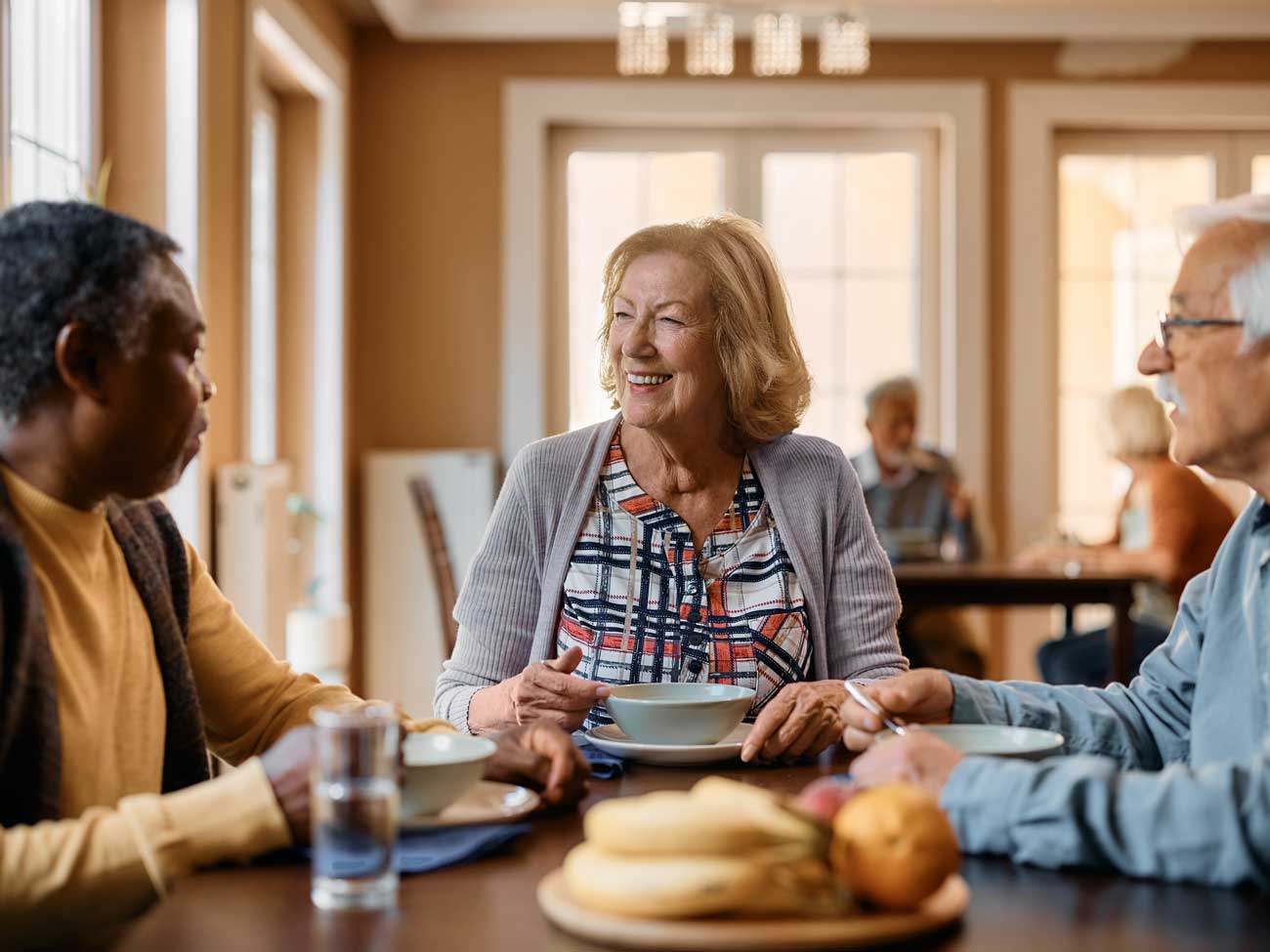 Three seniors chatting over breakfast at a dining table